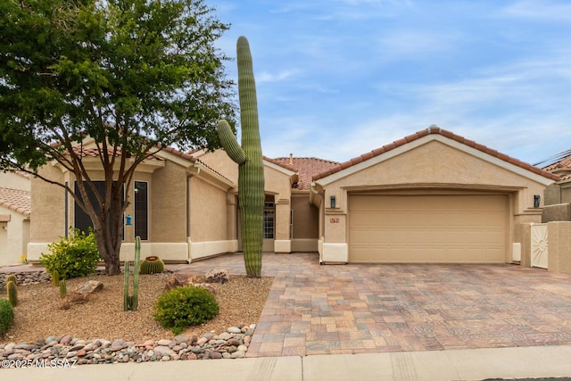 view of front of property with an attached garage, a tile roof, decorative driveway, and stucco siding