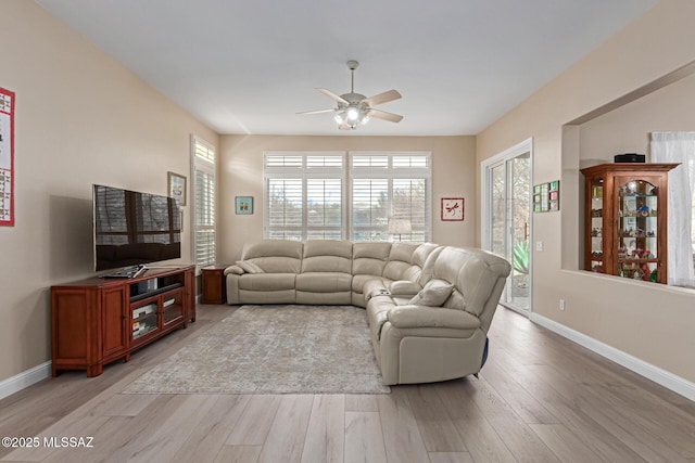 living area with a ceiling fan, baseboards, and light wood finished floors