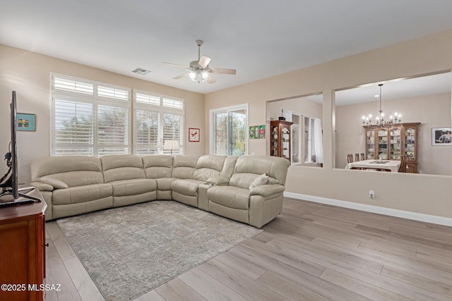 living area with baseboards, light wood finished floors, and ceiling fan with notable chandelier