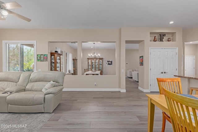 living room featuring baseboards, ceiling fan with notable chandelier, recessed lighting, and light wood-style floors