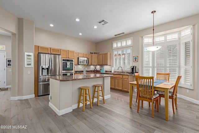 kitchen featuring visible vents, appliances with stainless steel finishes, a center island, dark stone counters, and decorative light fixtures