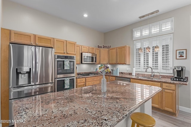 kitchen featuring light stone counters, a center island, stainless steel appliances, a kitchen bar, and a sink