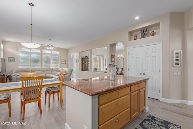 kitchen with light stone counters, open floor plan, hanging light fixtures, a wealth of natural light, and a center island