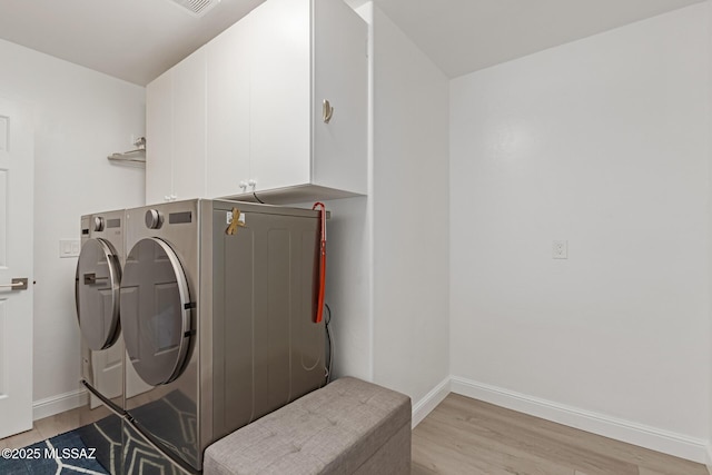 clothes washing area featuring baseboards, independent washer and dryer, cabinet space, and light wood-style floors