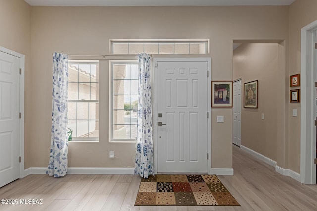 foyer with light wood-style flooring and baseboards