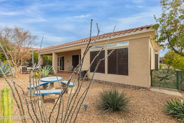 rear view of house featuring fence, a patio, a tiled roof, and stucco siding