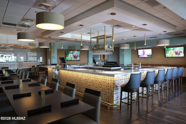 bar with a community bar, visible vents, wood finished floors, and decorative light fixtures