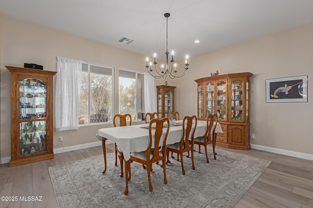 dining area featuring light wood-style floors, baseboards, visible vents, and a notable chandelier