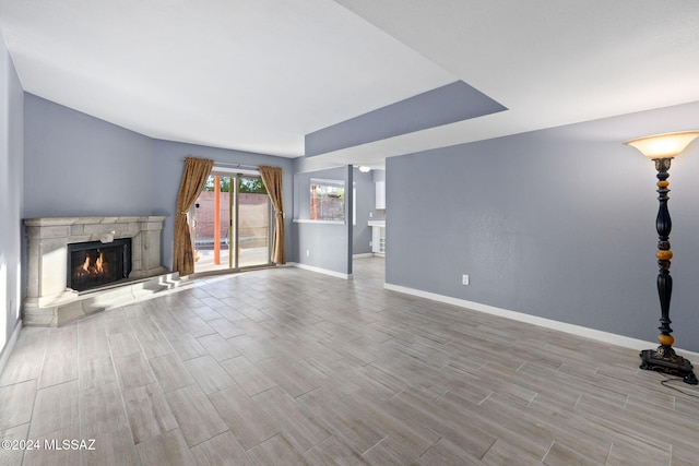 unfurnished living room featuring a stone fireplace