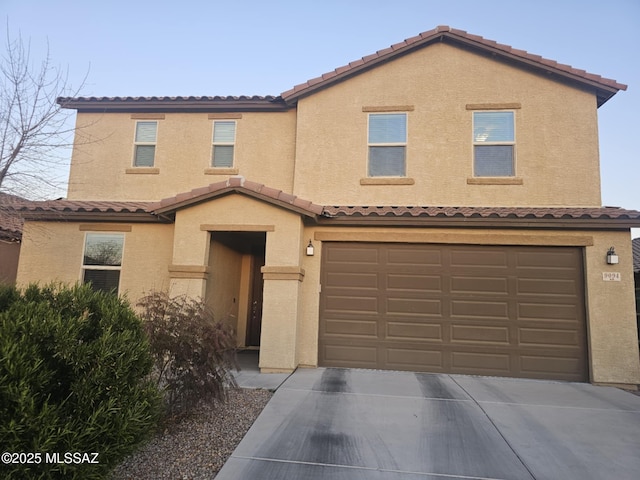 townhome / multi-family property featuring a garage, concrete driveway, a tile roof, and stucco siding