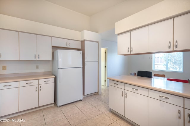 kitchen with white cabinetry, light tile patterned floors, and white fridge