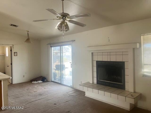 unfurnished living room featuring ceiling fan, lofted ceiling, carpet floors, and a tile fireplace