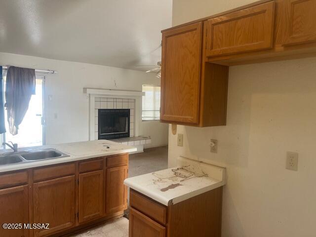 kitchen featuring sink, a tile fireplace, and ceiling fan