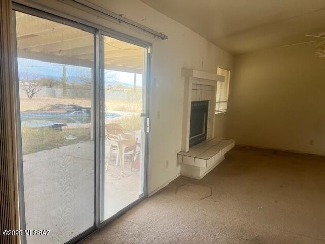 unfurnished living room featuring a tiled fireplace and light colored carpet