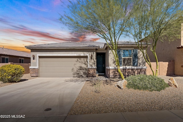 view of front of house featuring stucco siding, driveway, stone siding, an attached garage, and a tiled roof