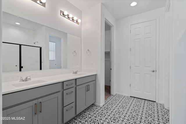 full bath with double vanity, baseboards, a stall shower, and a sink