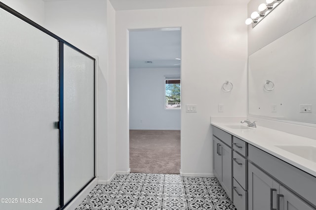 full bathroom featuring double vanity, a shower stall, baseboards, and a sink