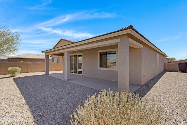 rear view of property with stucco siding, a patio, and a fenced backyard