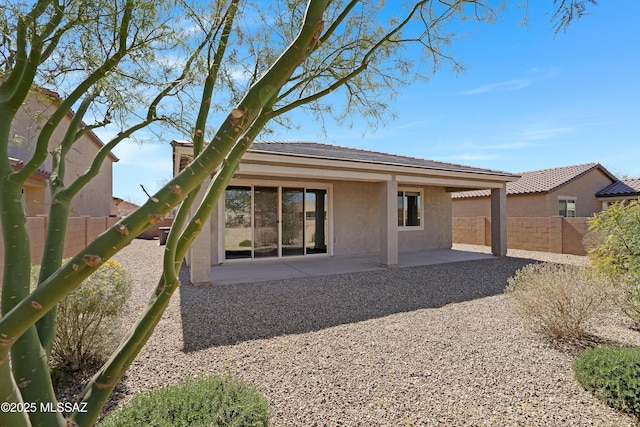 rear view of house with stucco siding, a fenced backyard, and a patio area