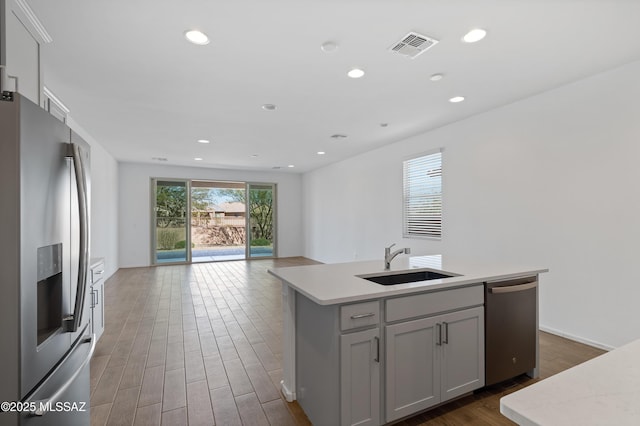 kitchen featuring visible vents, light countertops, wood finished floors, stainless steel appliances, and a sink