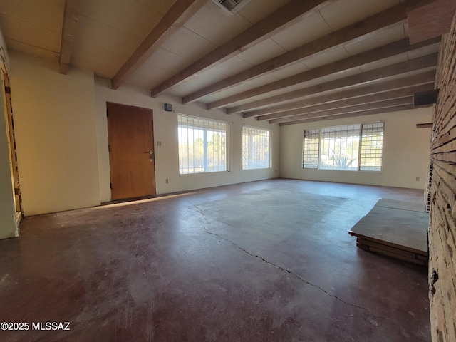 unfurnished living room featuring beamed ceiling and concrete floors