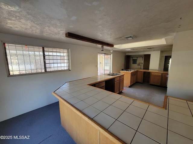 kitchen featuring tile countertops, a textured ceiling, dark carpet, and kitchen peninsula