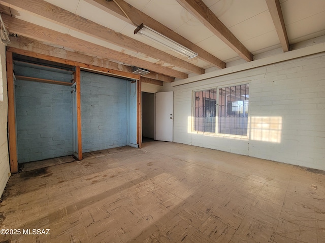 interior space with brick wall and beam ceiling