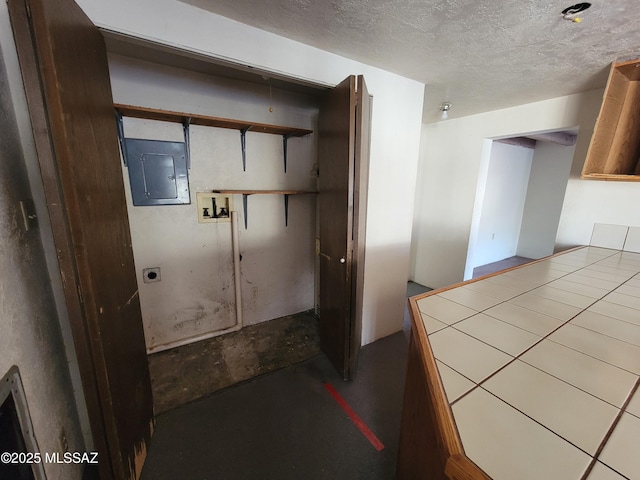 interior space with electric dryer hookup, hookup for a washing machine, electric panel, and a textured ceiling