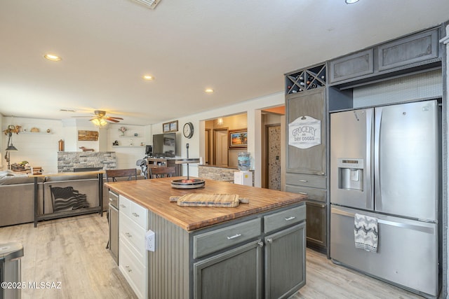 kitchen featuring stainless steel fridge, gray cabinets, ceiling fan, a center island, and light wood-type flooring