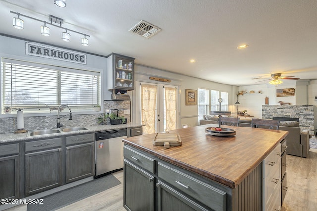 kitchen with sink, decorative backsplash, a center island, stainless steel dishwasher, and light hardwood / wood-style floors