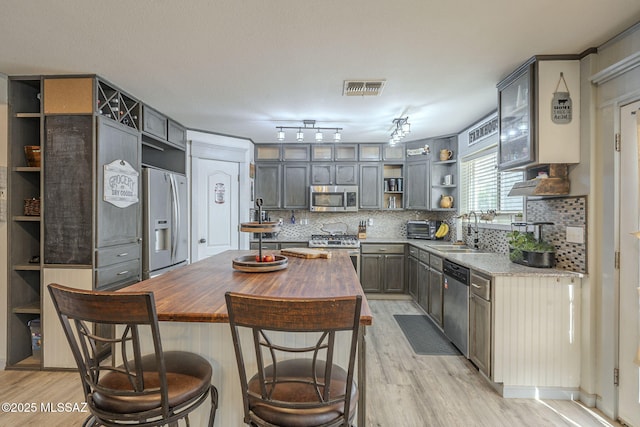 kitchen with sink, light wood-type flooring, gray cabinets, stainless steel appliances, and backsplash