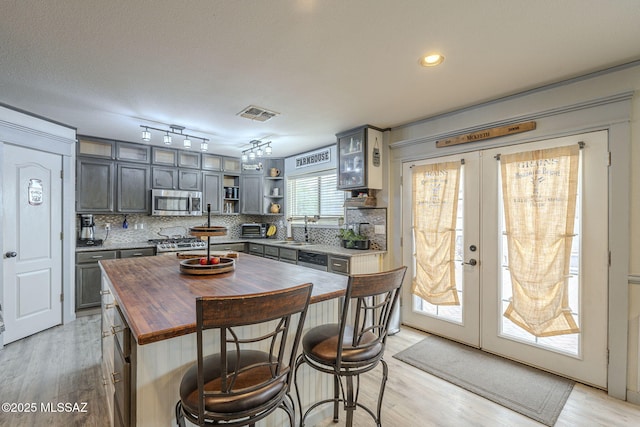 kitchen with gray cabinetry, tasteful backsplash, french doors, and appliances with stainless steel finishes