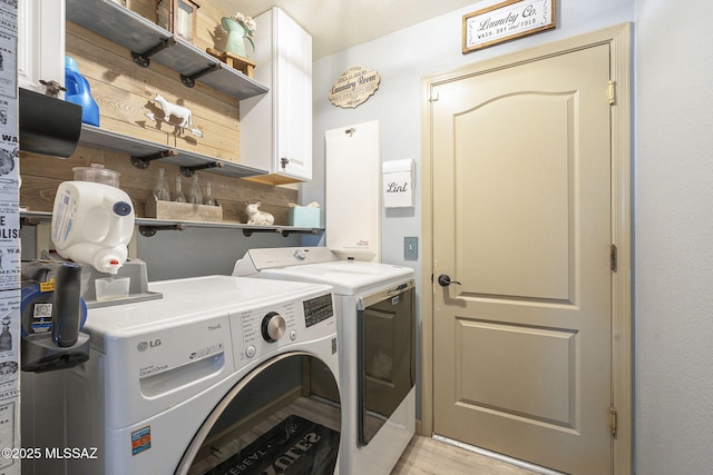 washroom featuring cabinets, washer and clothes dryer, and light hardwood / wood-style floors