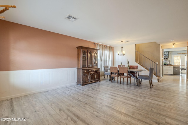 unfurnished dining area with a notable chandelier and light hardwood / wood-style flooring