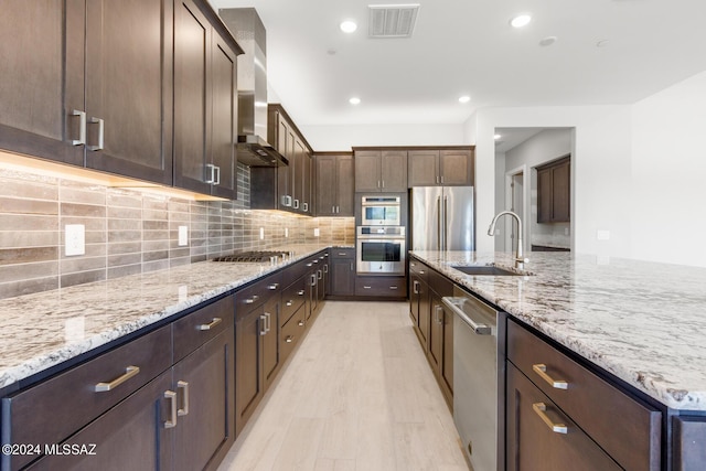 kitchen featuring sink, appliances with stainless steel finishes, backsplash, dark brown cabinets, and light stone counters