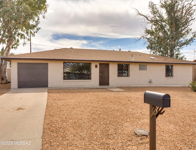 single story home featuring an attached garage, a shingled roof, driveway, and brick siding