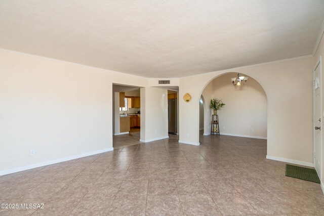 unfurnished room featuring baseboards, visible vents, arched walkways, and a notable chandelier