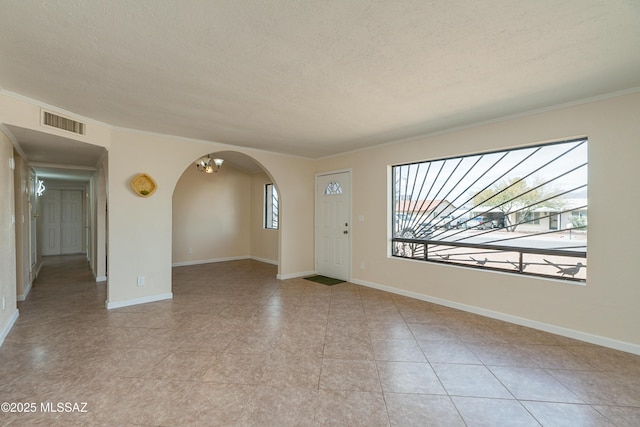 interior space with arched walkways, crown molding, a textured ceiling, and visible vents