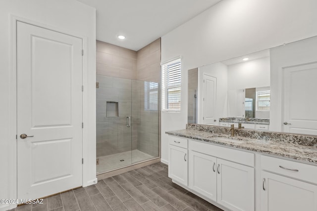 bathroom featuring a shower with door and vanity