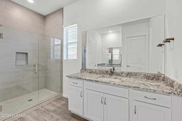 bathroom featuring vanity, a healthy amount of sunlight, and a shower with shower door