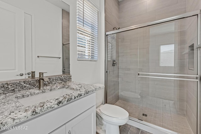 bathroom featuring vanity, toilet, and a shower with shower door