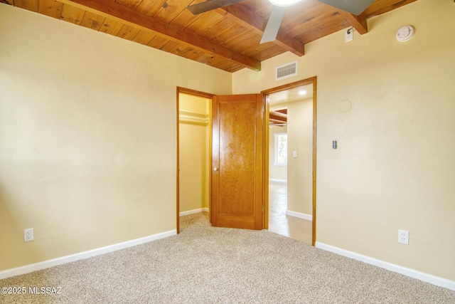 unfurnished bedroom featuring light colored carpet, beam ceiling, and wooden ceiling