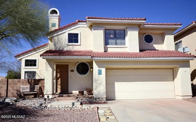 mediterranean / spanish home featuring stucco siding, a tiled roof, concrete driveway, and fence