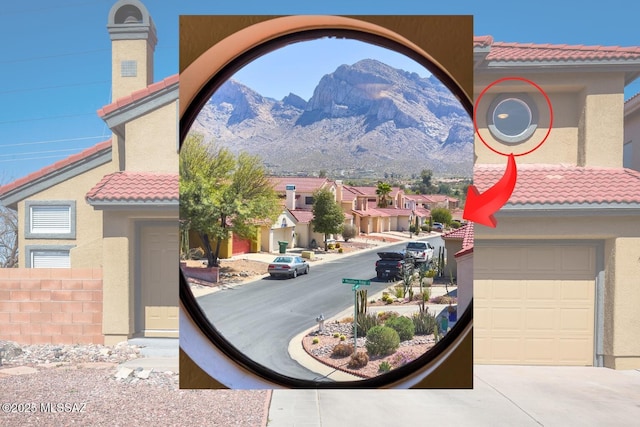 details with a mountain view, stucco siding, a tiled roof, and concrete driveway