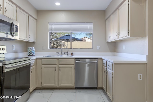 kitchen featuring recessed lighting, a sink, light countertops, appliances with stainless steel finishes, and marble finish floor