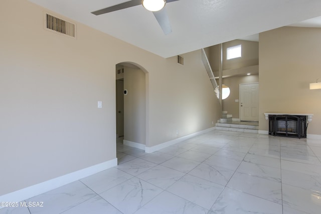 unfurnished living room featuring baseboards, visible vents, arched walkways, and marble finish floor