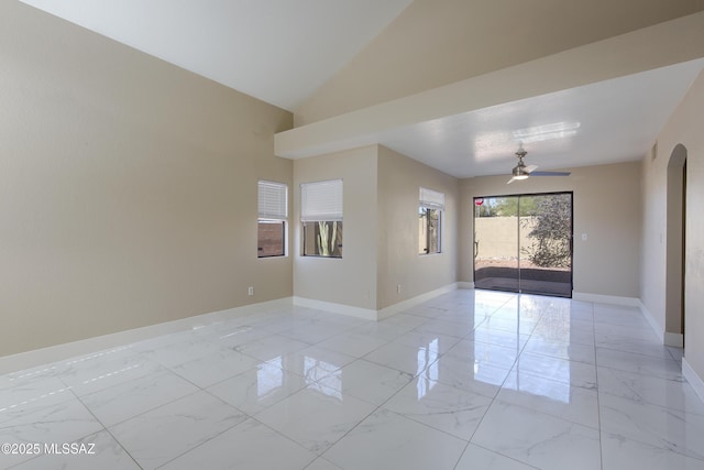 spare room with a ceiling fan, baseboards, arched walkways, vaulted ceiling, and marble finish floor