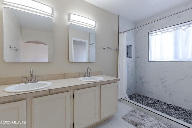 full bathroom with a marble finish shower, marble finish floor, and a sink
