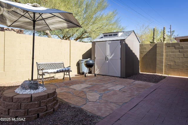 view of patio / terrace featuring a storage shed, a fenced backyard, an outbuilding, and grilling area