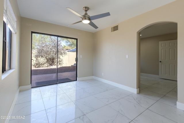 spare room with visible vents, marble finish floor, arched walkways, baseboards, and ceiling fan